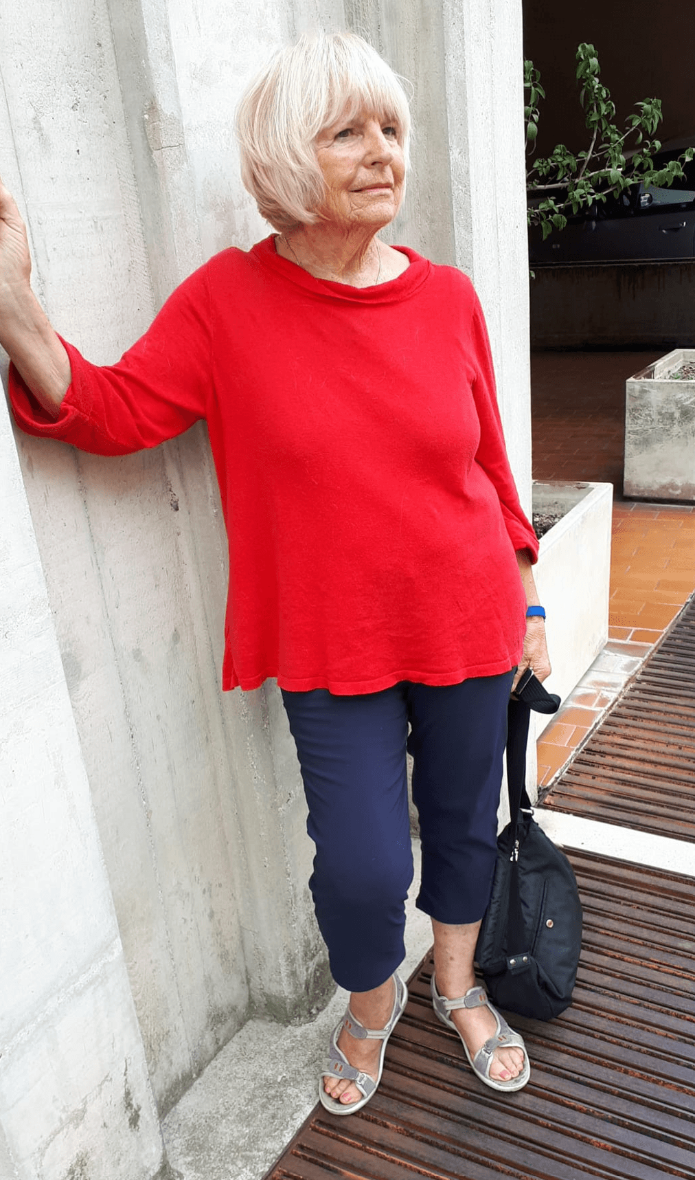 Marianne Igel wearing a red top and dark blue trousers beside a light stone wall